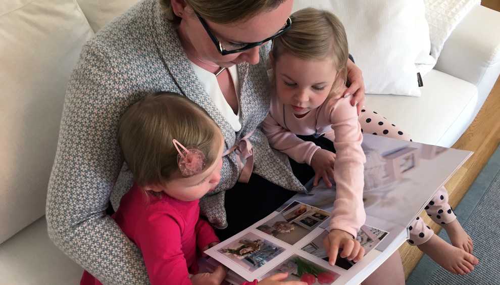 Äiti ja lapset selaavat lapsuusmuistoja kuvakirjasta Äiti ja lapset selaavat lapsuusmuistoja kuvakirjasta