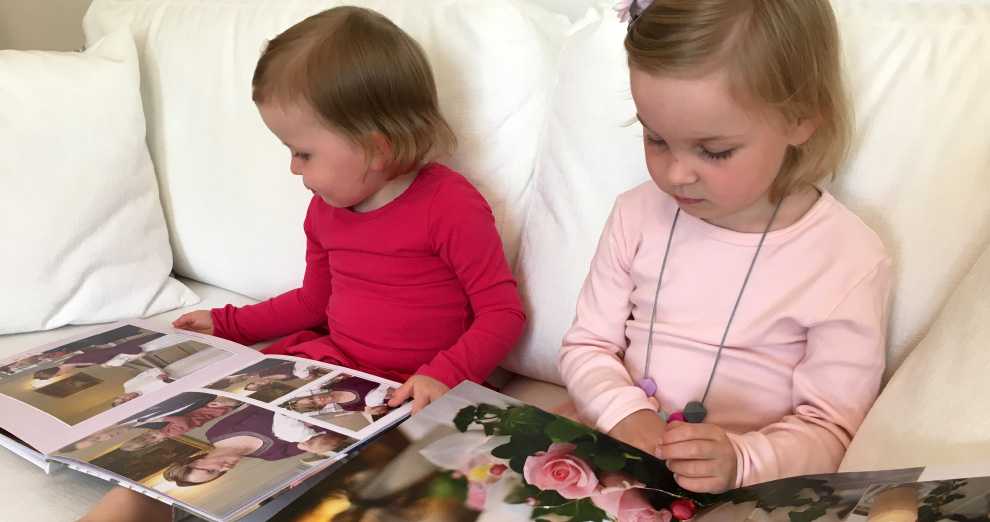 Tytöt selaavat sohvalla kuvakirjaa Tytöt selaavat sohvalla kuvakirjaa