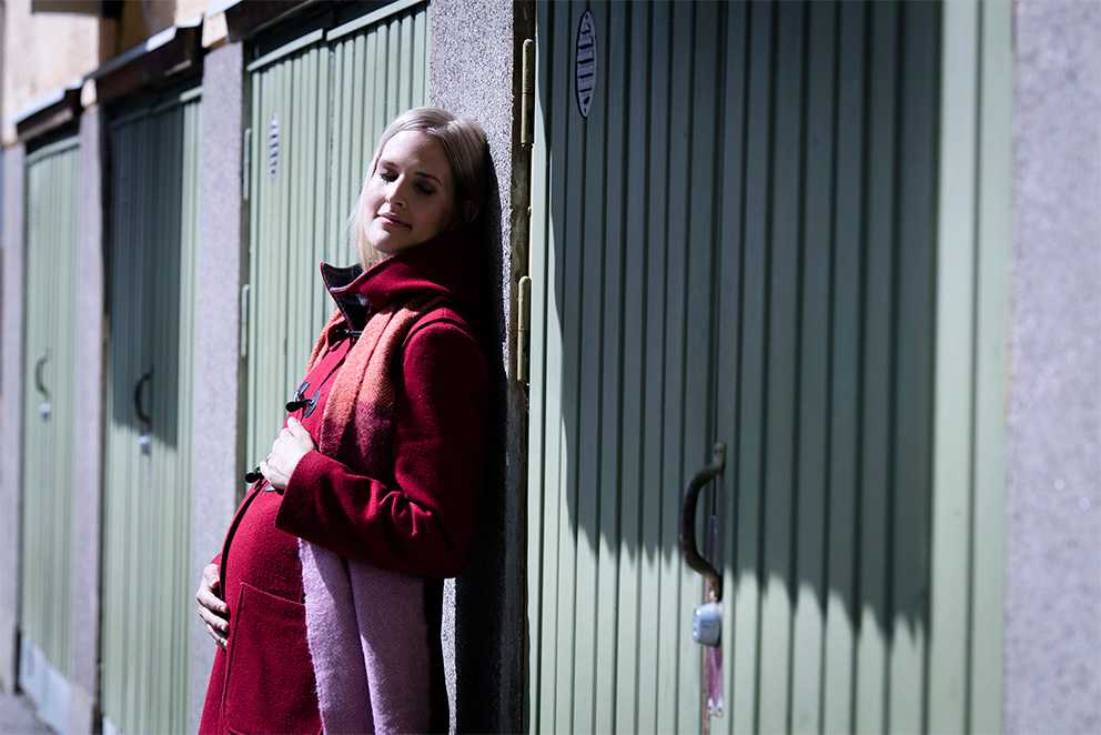 Raskaana oleva nainen nojaa talon seinään Raskaana oleva nainen nojaa talon seinään